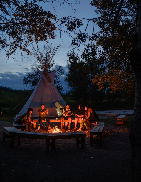 A teepee with a fire burning outside at nighttime