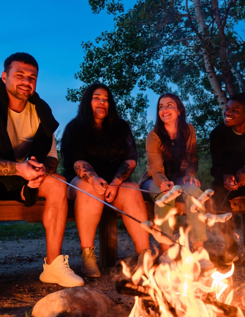 Four individuals roasting marshmallows 