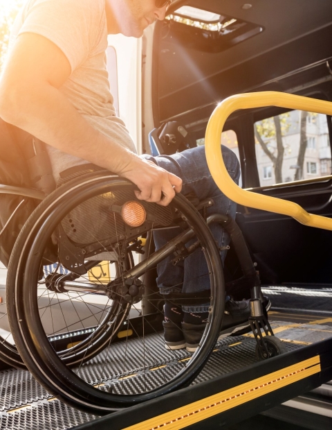 An man in a wheelchair boarding a bus using a chair lift. 