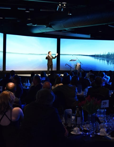 Man on stage presenting in front of a crowd