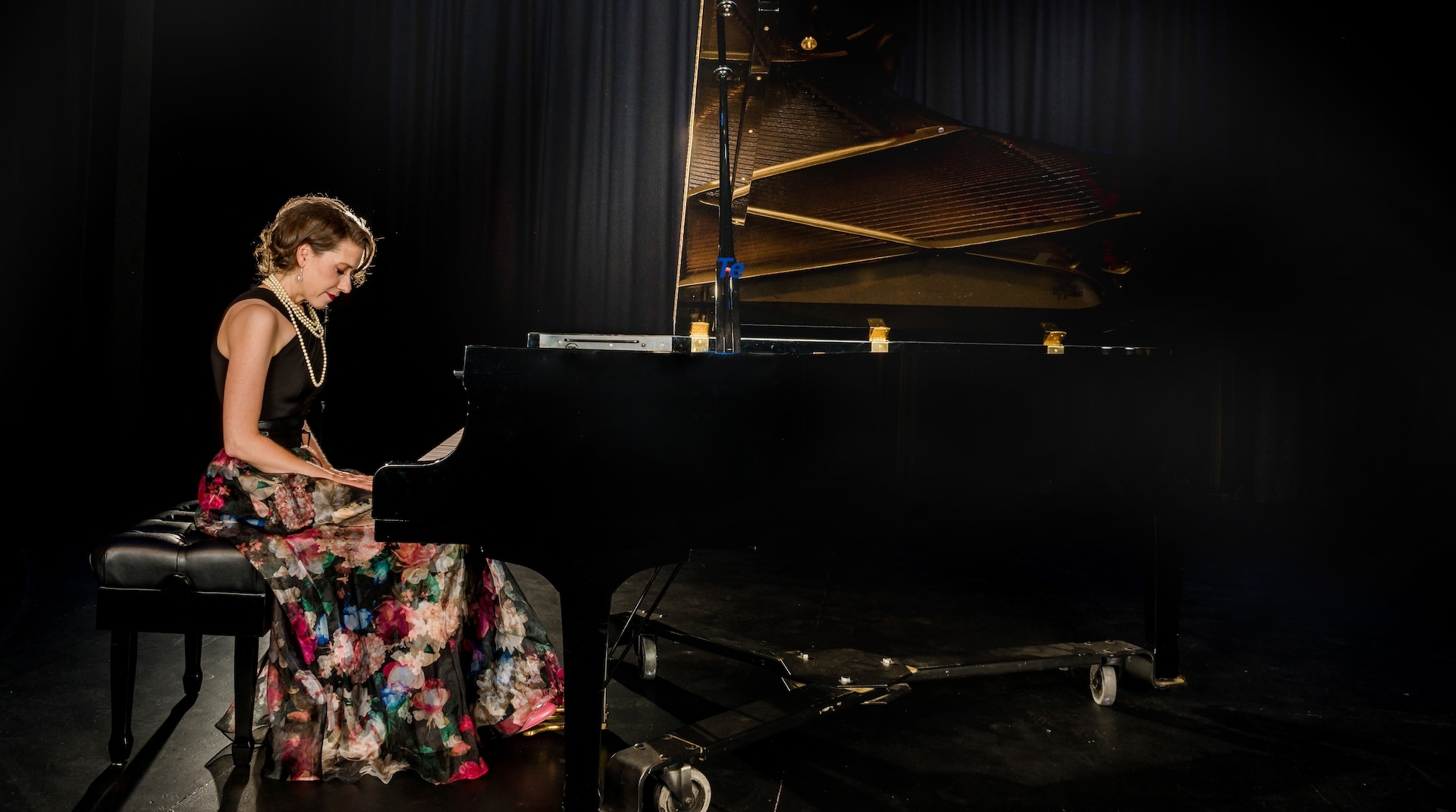 Sarah Hagen sits at a grand piano. 