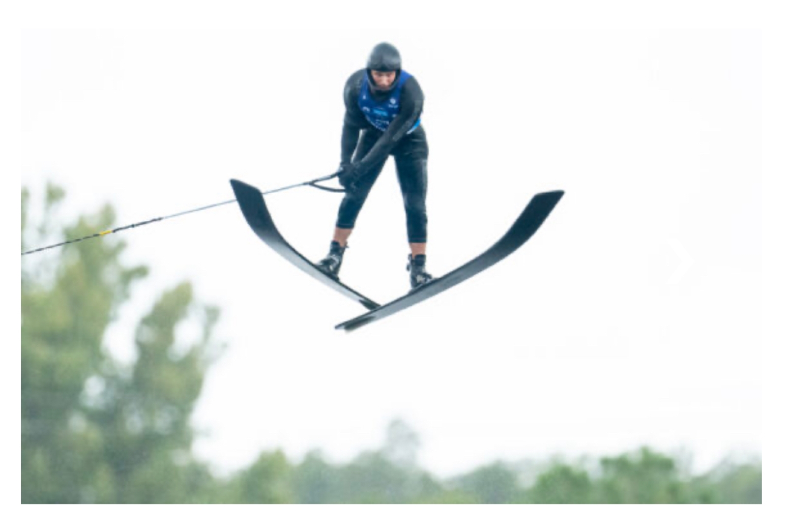 A professional waterski jumper soaring a distance of 70 m off a 1.8 m high jump