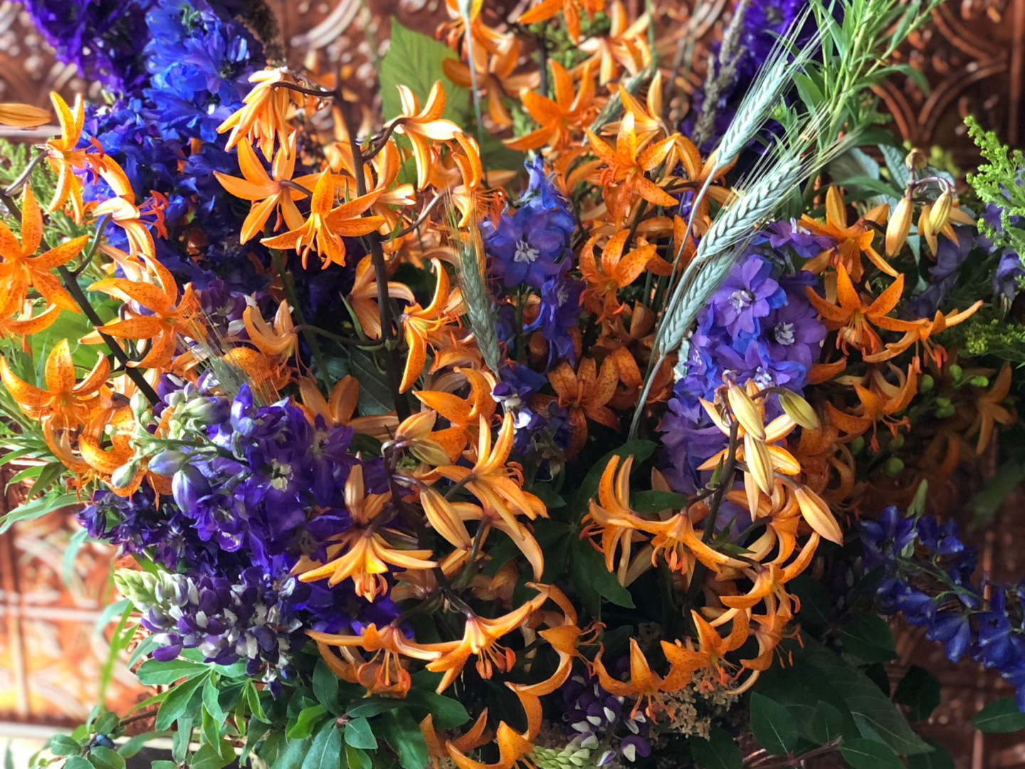 Purple and orange flower arrangement with wheat accents made at the Black Fox Flower Class