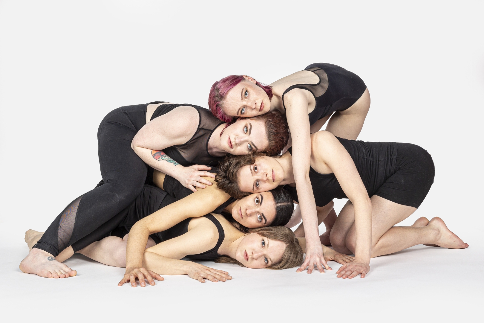 dancers laying down with stacked heads looking outwards