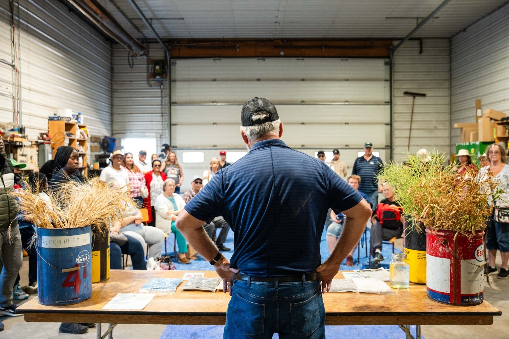 Photo of producer sharing the grains that they grow at their farm to guests in their equipment shed. 