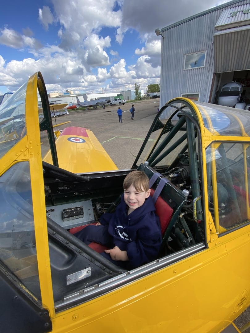 Future pilot seated at the flight controls of a vintage Harvard RCAF Training aircraft.