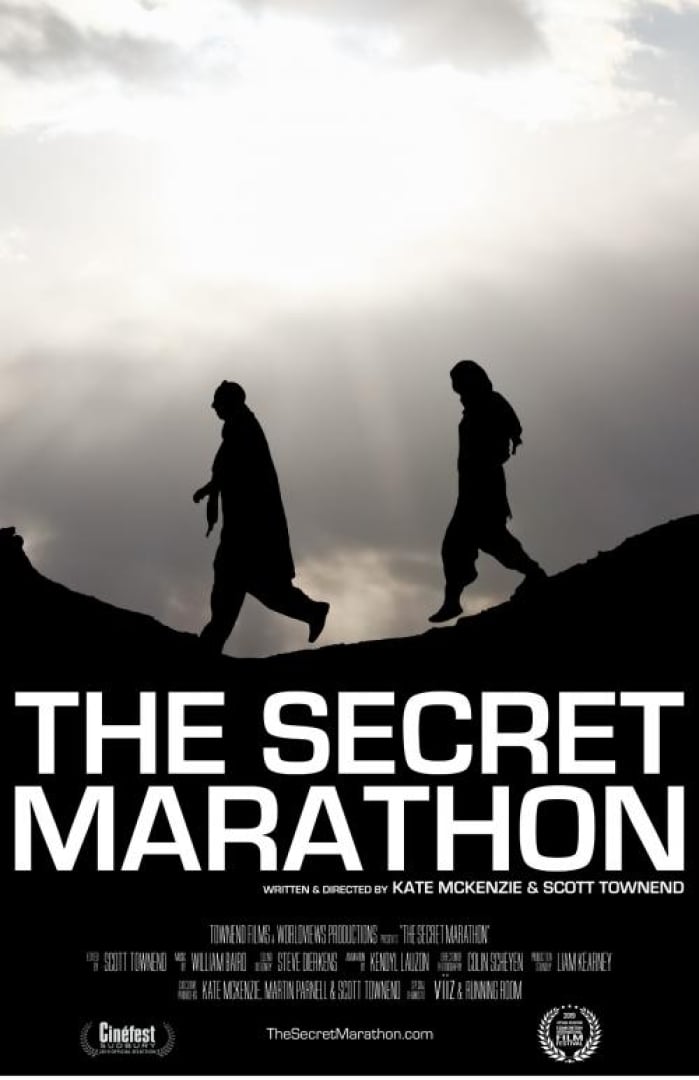 Image of the movie; the secret marathon. Shows two people walking on a hill with the sun shining down on them. 