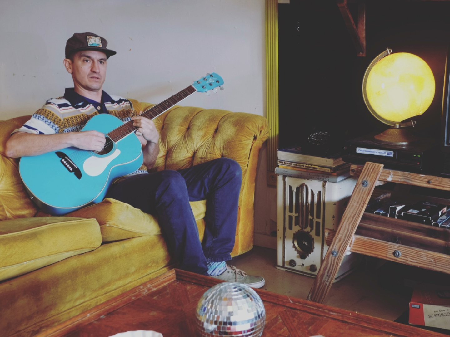 Wax playing guitar on a yellow couch