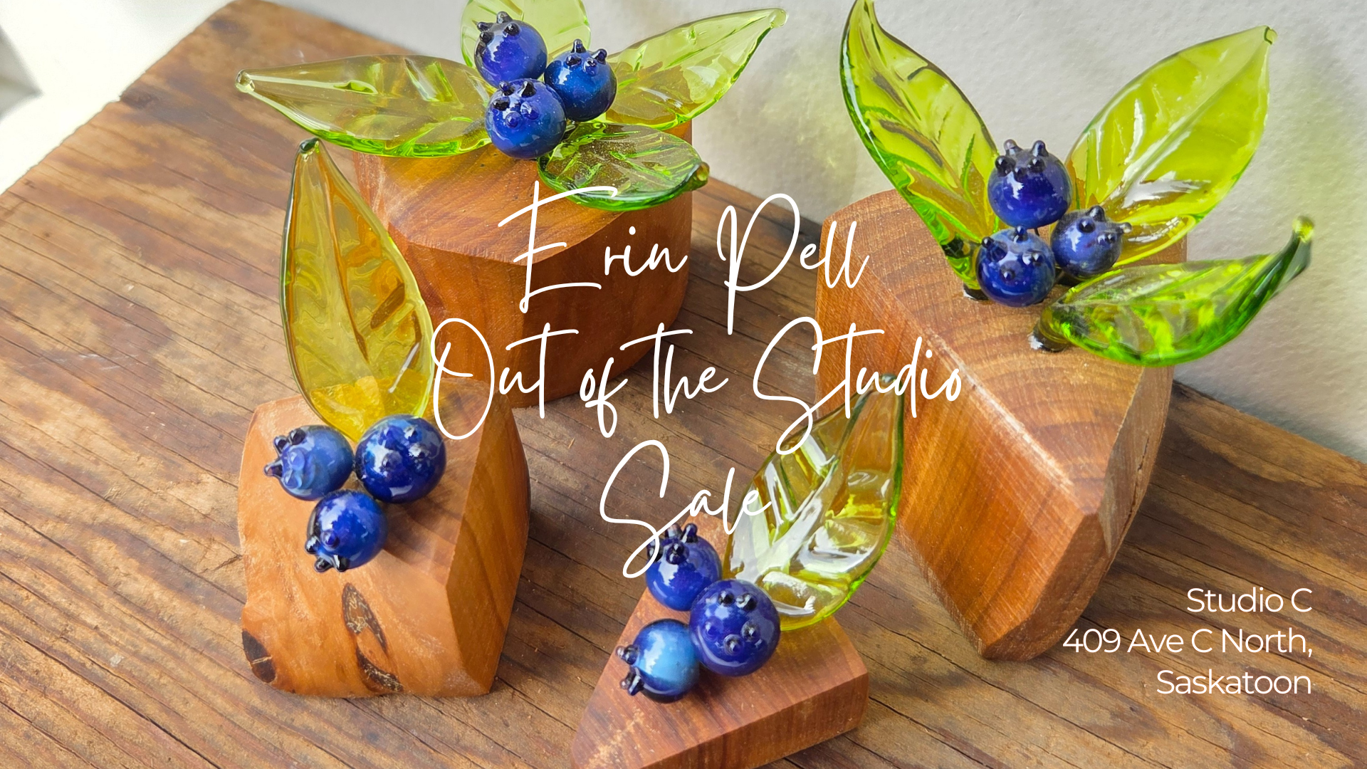 glass blueberries with transparent green leaves on orangey wood bases with event detail written in white script