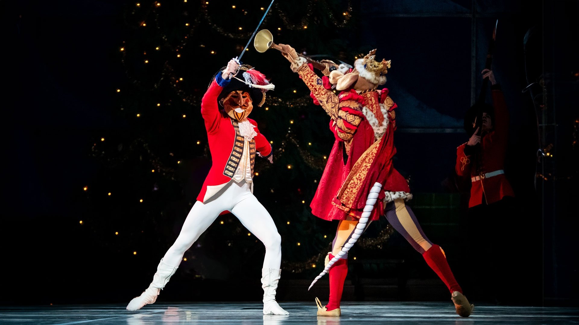 An image of two people fencing in costumes on stage.