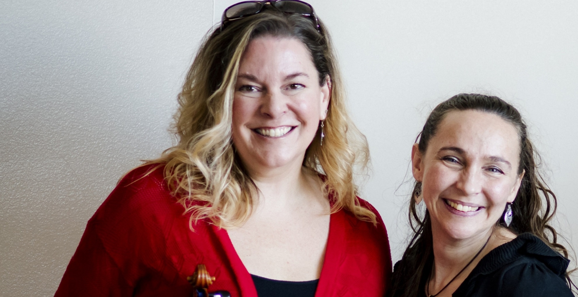 Kim de Laforest in Red holding a violin, with Anna Marie Bekolay both smiling