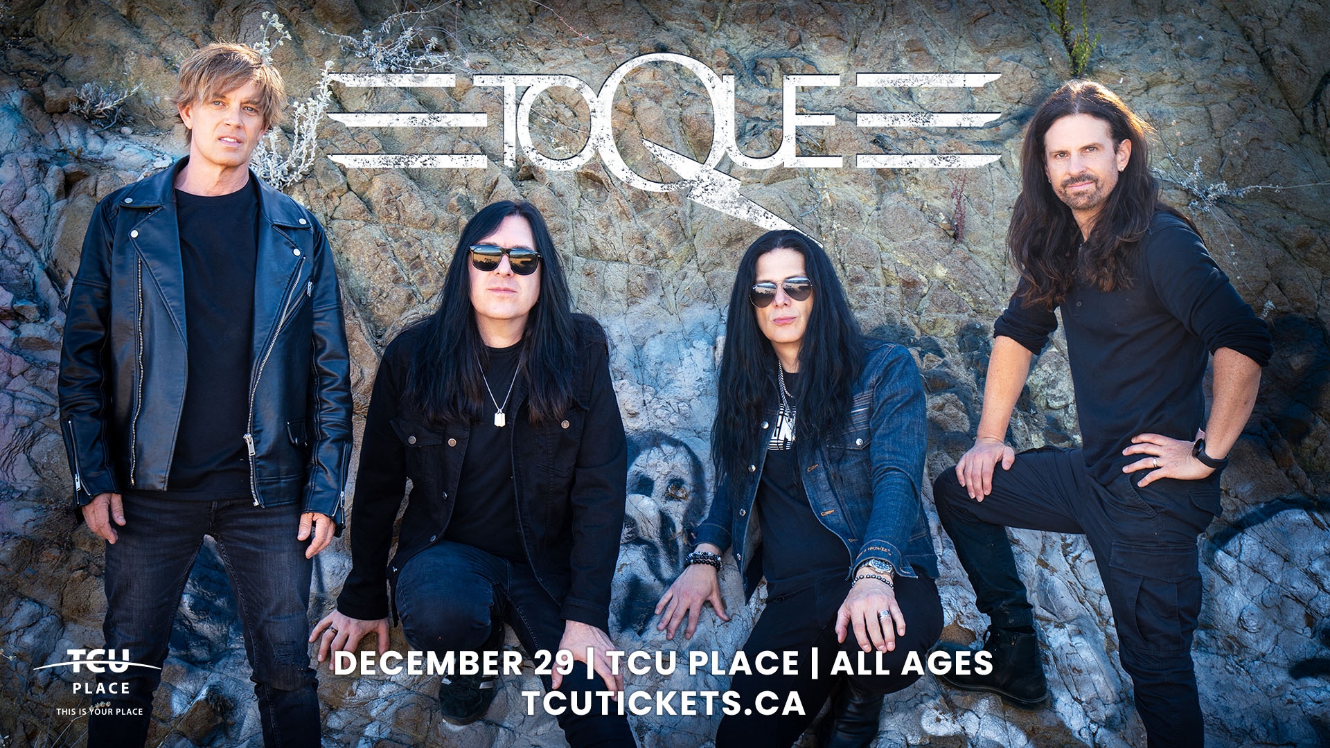 An image of four men, TOQUE, posing in front of a rock. 