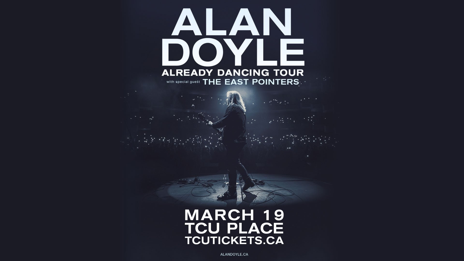 A picture of a man on stage with a guitar, a spotlight on him.