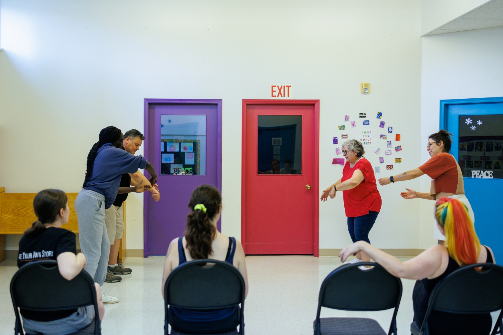 A group of people in a classroom playing improv games in front of other students in the class.