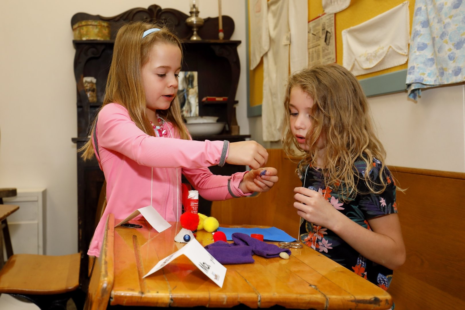 A young child is showing her craft to another child. 