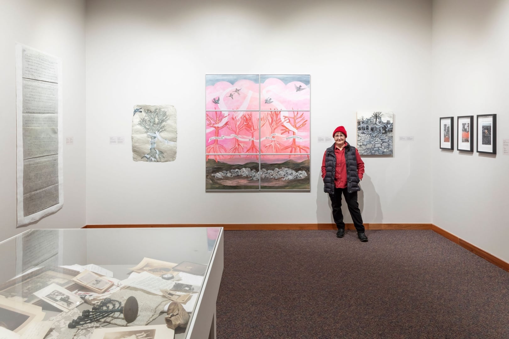 Image of the artist Betsy Rosenwald standing next to one of her paintings titled Homage in the museum's gallery.
