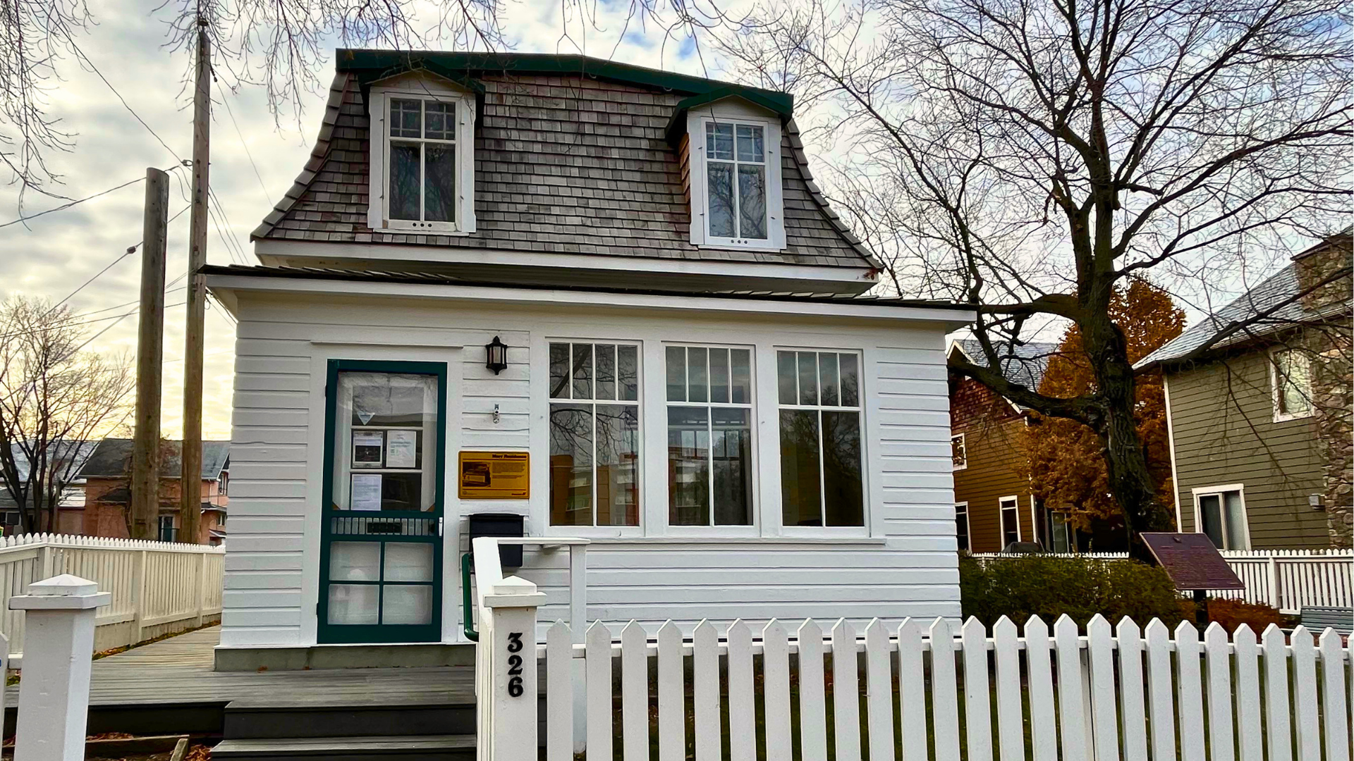 exterior of a historic home, white with green trim, a white picket fence 
