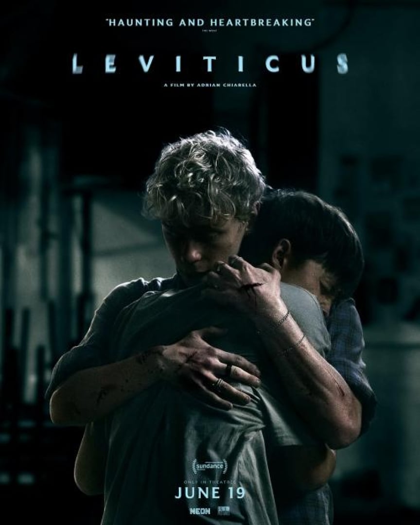 Image of two boys hugging eachother with cuts all over their arms, standing in the dark.