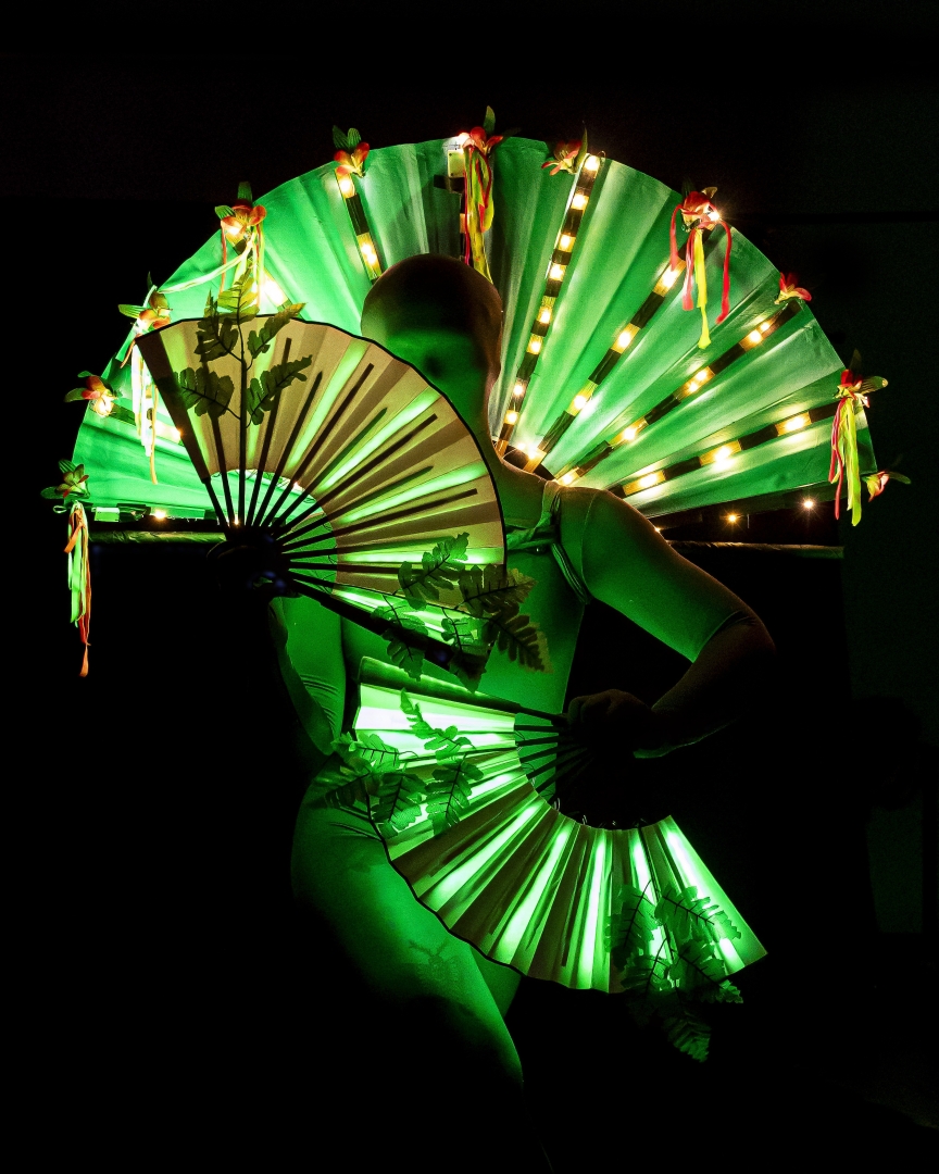 An alien dances with green fans