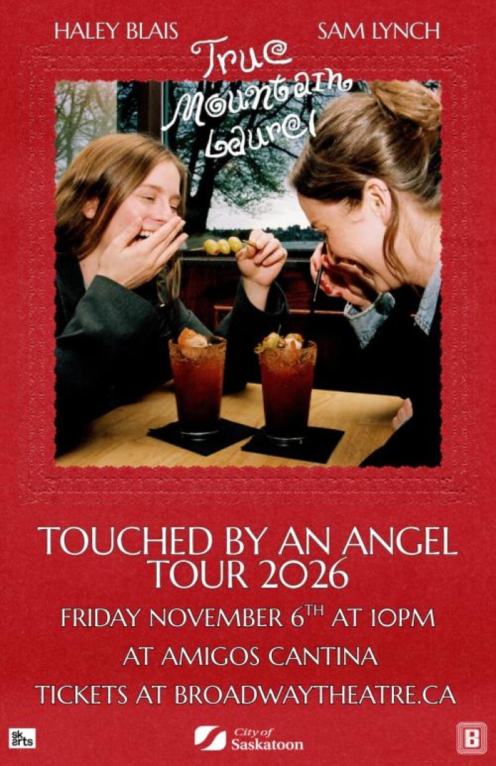 Image of two women laughing at a table over caesar drinks with olives. 