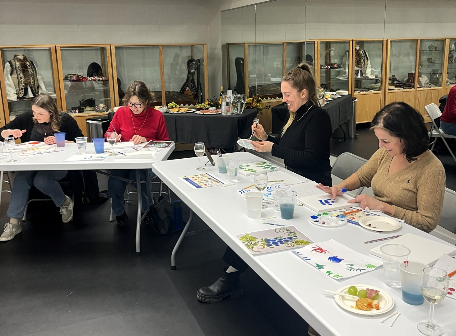 An image of participants sitting at the table and painting at one of the Petrykivka & Wine Nights